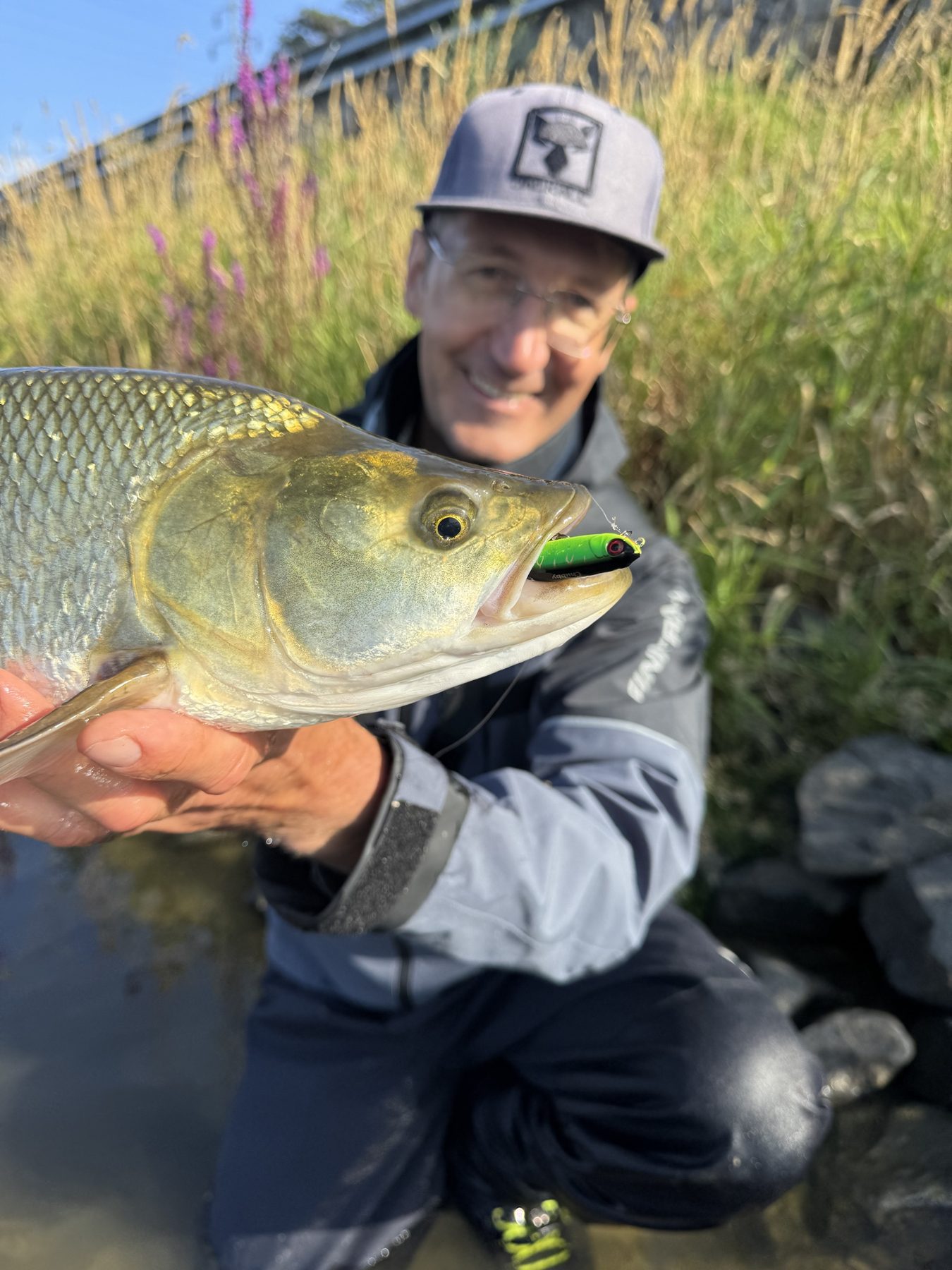 Oleg smiling behind an asp caught on a bright green lure
